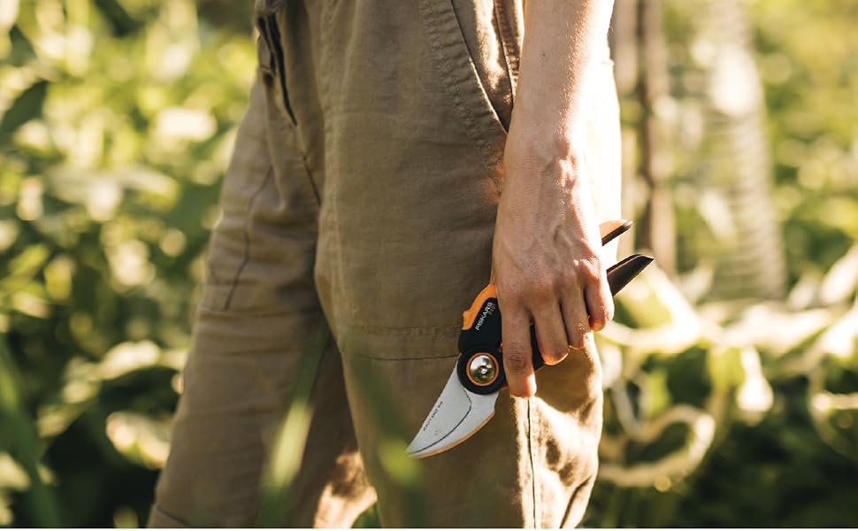 Person holding an orange and black pruner with SoftGrip.
