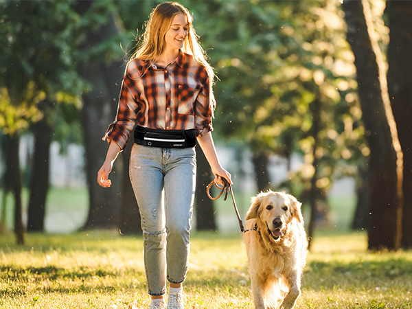 Plaid shirt and jeans worn by person walking golden retriever dog in park with trees in background.