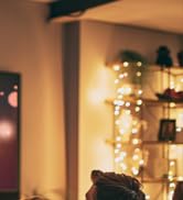 Partial view of a dimly lit interior with string lights and decorative objects visible in the background.