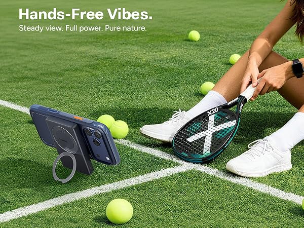Woman with tennis racket uses phone on kickstand power bank.