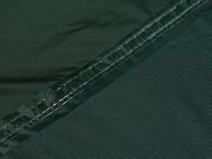 Close-up of dark green fabric with visible double stitching, showing seam construction and material texture.
