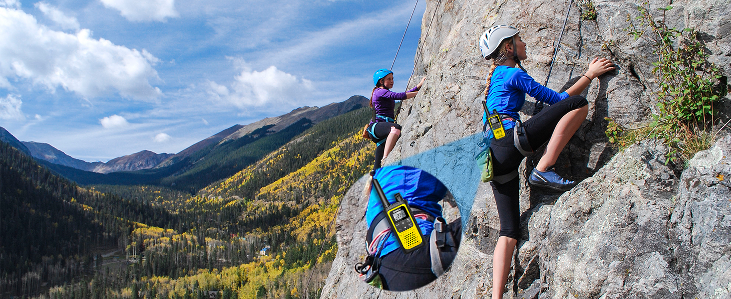 Hikers climbing a rock wall use yellow walkie talkies clipped to their belts for easy communication