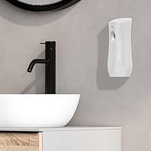 Battery-operated air freshener on bathroom wall near mirror for timed fragrance release.