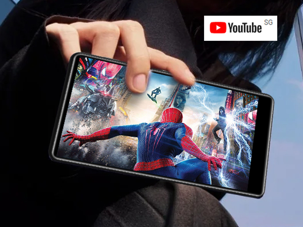 Smartphone displaying a vibrant action movie scene with superhero characters, held in a person's hand. YouTube logo visible in corner.
