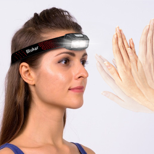 Black adjustable headband or visor with white trim, shown being worn against a neutral background with decorative hand elements.