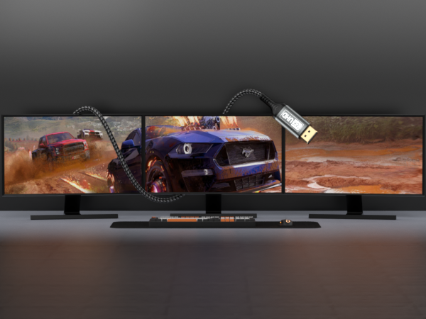 Triple-monitor gaming setup displaying racing game scenes. Curved widescreen displays mounted on stands. USB device connected with coiled cable, suggesting high-performance gaming peripherals.