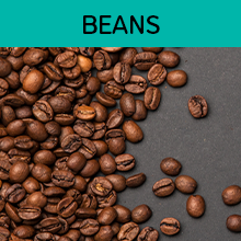 A handful of coffee beans poured on a black tabletop