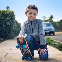 Boy with skateboard outside on the sidewalk.