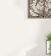 Minimalist interior setting with white walls, showing partial view of wall art and indoor plant in corner.