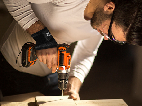 a man using a drill to cut a piece of wood.