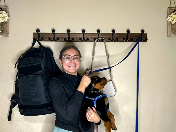 In front of the wall coat rack, a girl is happily hugging her dog.