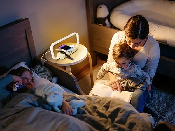 Bedroom scene with curved desk lamp illuminating nightstand in warm light during evening hours.