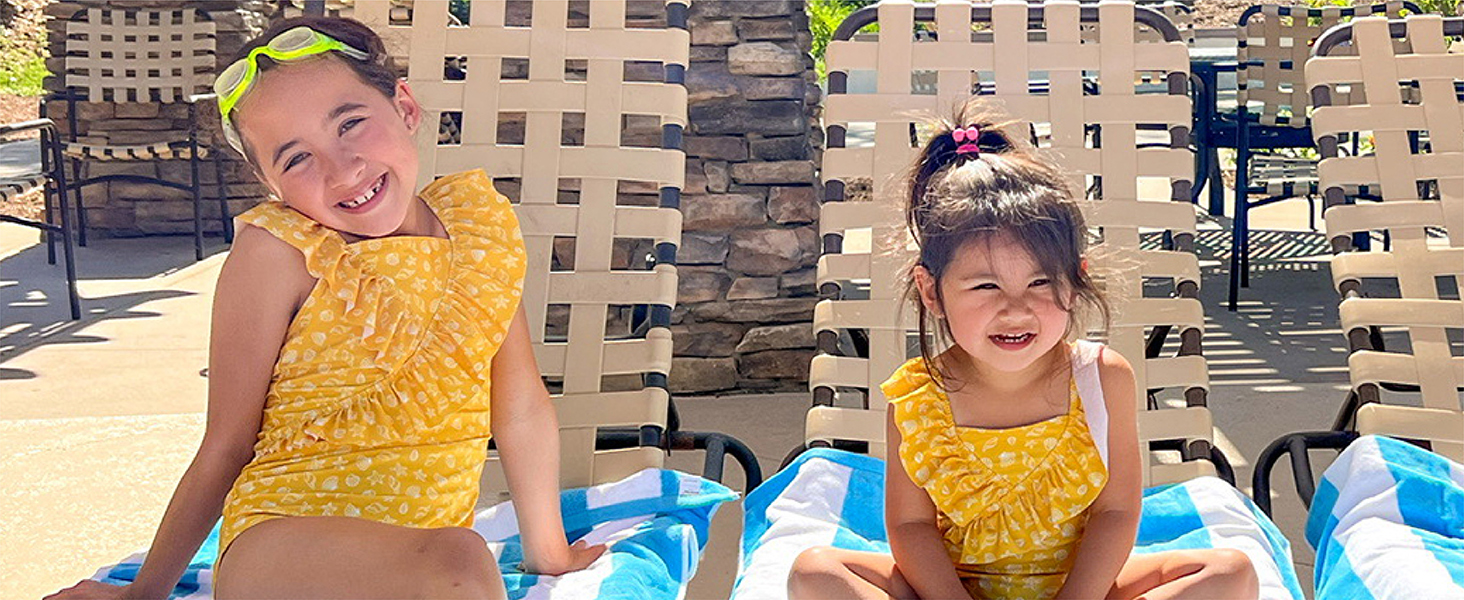 More little girls in summer clothes, smiling while together with beach towels