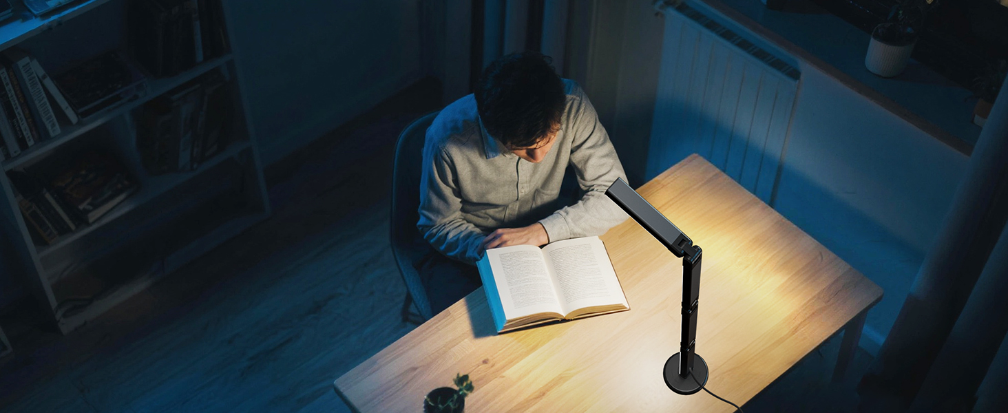 Person using what appears to be a desk lamp or light fixture in a dark setting, illuminating a work surface.