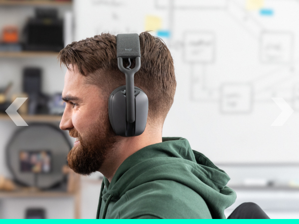 An angle image of a man wearing Zone Vibe 100 (Graphite) and working on a computer