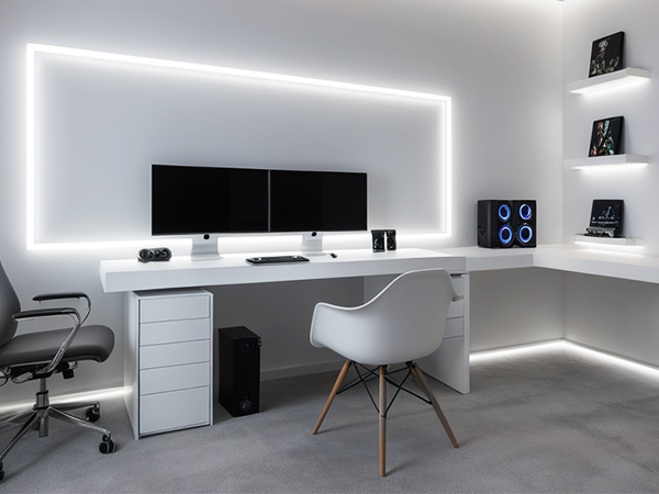 Modern minimalist workspace with LED ambient lighting, featuring white desk, dual monitors, and built-in wall shelving with integrated lighting strips.