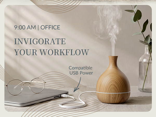 Wood grain vase essential oil diffuser on office desk connected to laptop via white USB power cable.