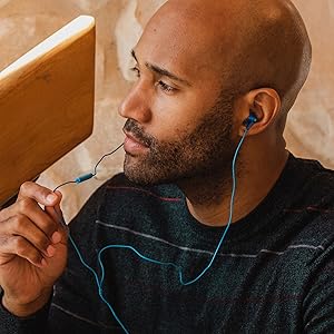 african american man wearing blue earbuds speaking to a microphone