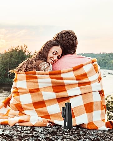Couple sit by the lake peering at horizon as sun goes down over trees