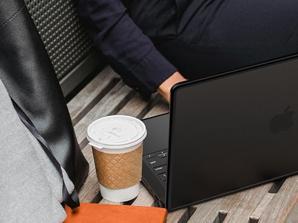 Person in black leather chair working on black laptop computer with disposable coffee cup nearby.