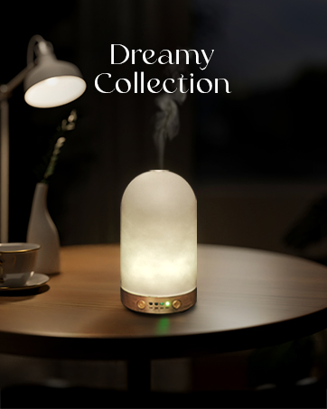 Text reads 'Dreamy Collection'. Illuminated dome-shaped lamp with decorative base on wooden surface, creating ambient lighting in dark setting.