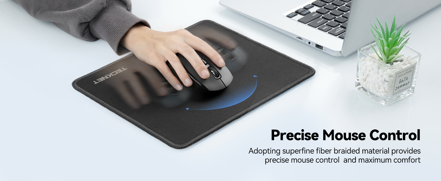 Black mousepad with hand using mouse. Features blue circular design. Laptop and small plant visible. Text mentions 'Precise Mouse Control' and 'superior fiber material'.