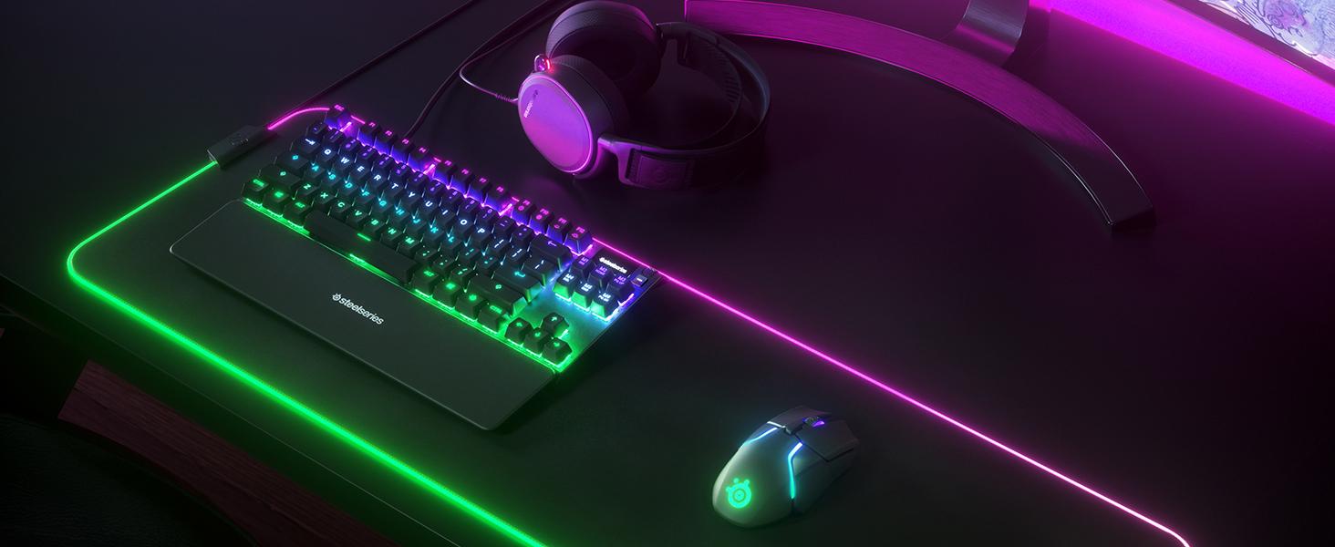 - A SteelSeries desk setup with Apex TKL keyboard, Rival mouse, Arctis headset, and QcK mousepad