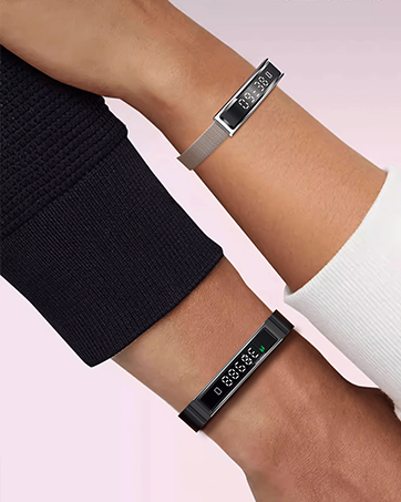 Close-up of two matching black fitness or sports bands worn on forearms against pink background, showing adjustable strap design.