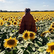 Lady wearing orange blanket in a field of sunflowers