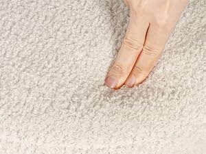 Close-up of fingers touching light-colored carpet or fabric, demonstrating texture or softness.