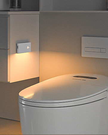 Modern bathroom featuring a white toilet with built-in bidet functionality. Wall-mounted controls and ambient lighting visible.