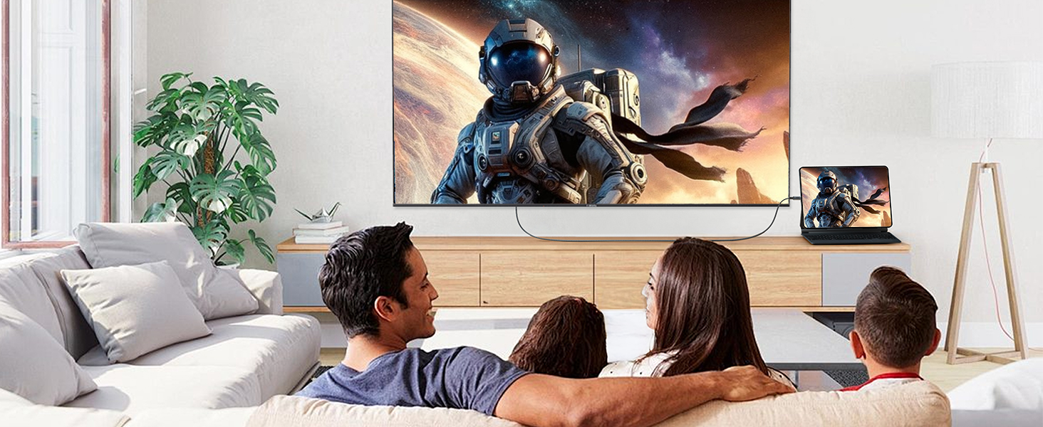 Family watching large TV displaying space-themed video game or movie. Smaller screen on table shows matching content. Living room setting with plant and wooden furniture.