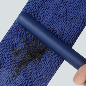 a hand holding a blue carpet with a black stain on it.