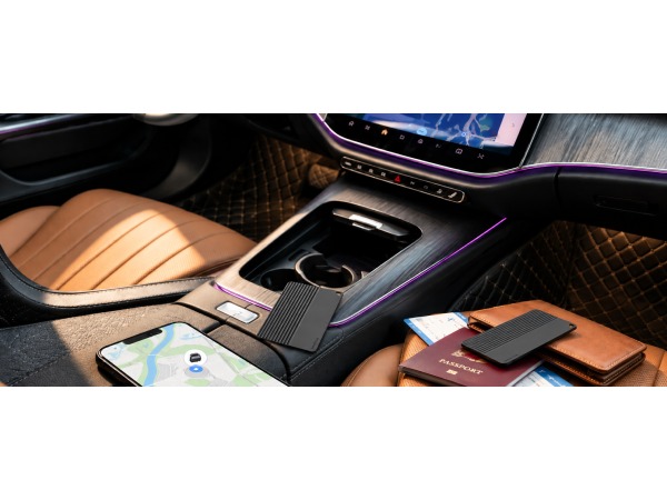 Slim tracker card, black, placed inside a car with a passport, wallet and smartphone.