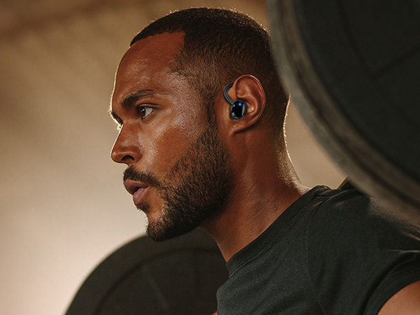 a man wearing a bluetooth earbuds in a gym