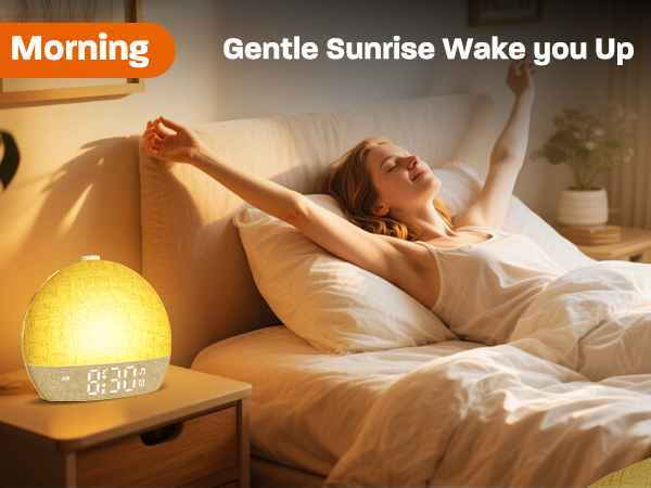 Text reads 'Morning Gentle Sunrise Wake you Up'. Bedroom scene with person stretching in bed next to glowing yellow sunrise-simulation alarm clock.