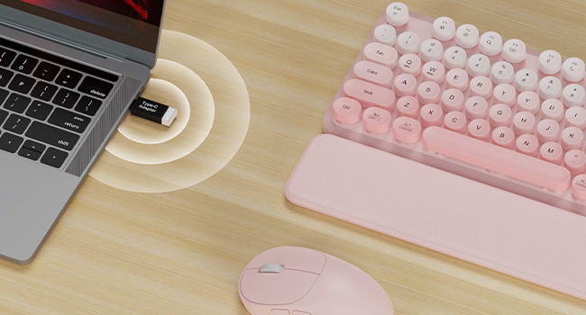 USB receiver plugged in laptop connects pink wireless keyboard mouse combo with wrist rest on desk