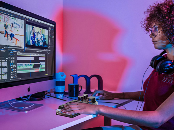 a woman sitting at a desk with a computer and a video game on the screen.