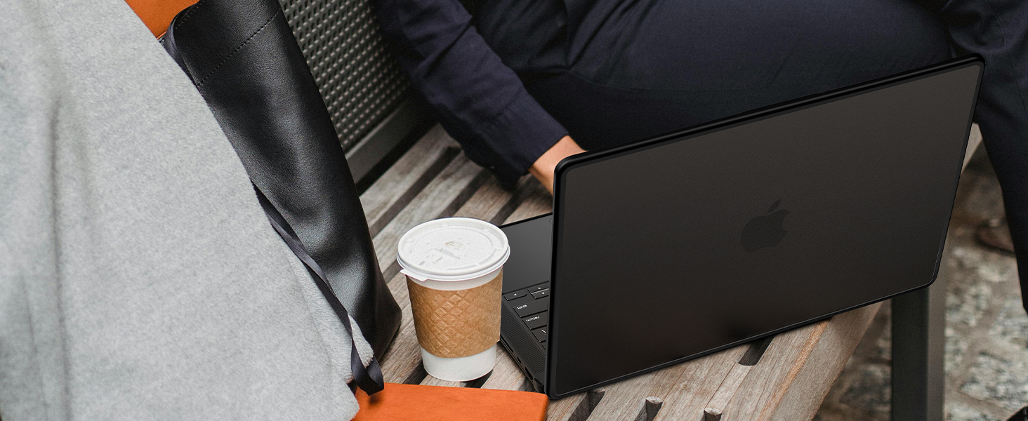 Person in black leather chair working on black laptop computer with disposable coffee cup nearby.
