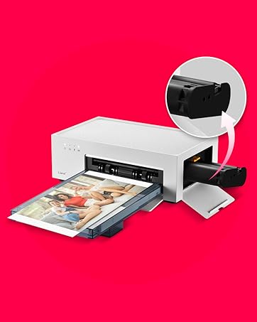 White photo printer with open paper tray, printing a color photograph. Inset image shows black ink cartridge being inserted into the top of the printer.