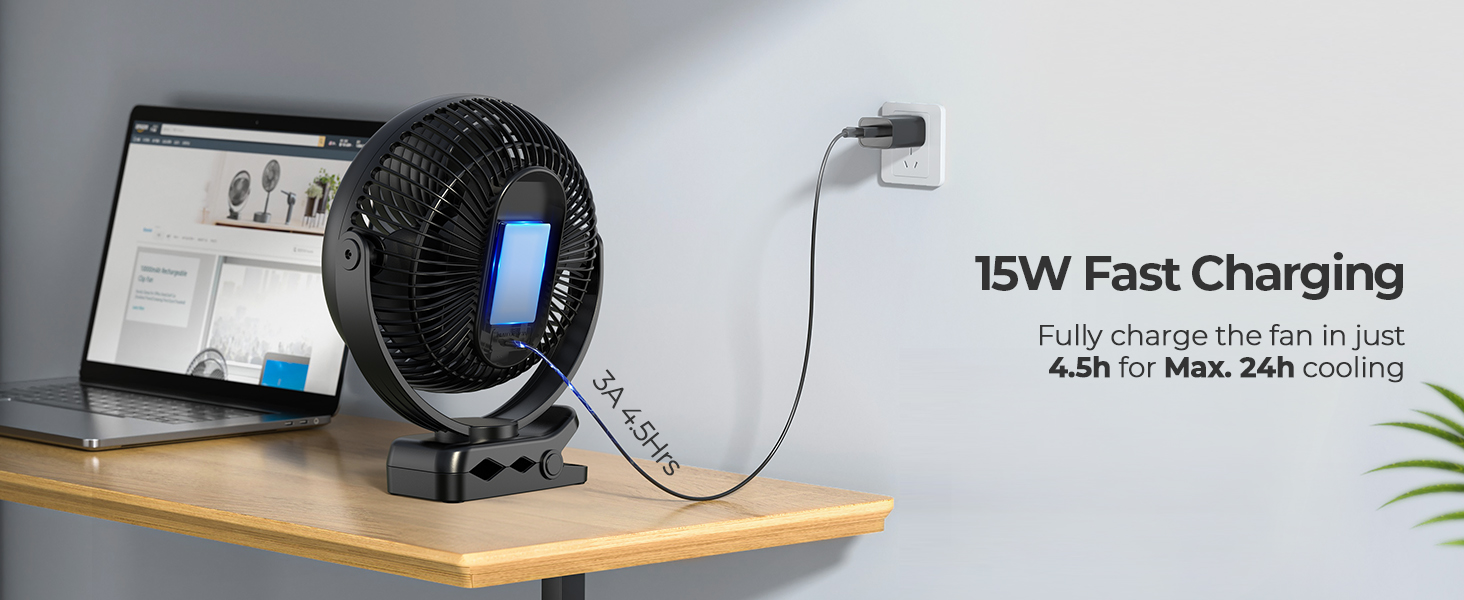 Desk fan with integrated phone holder, featuring 15W fast charging capability. Black circular design with blue-lit display on wooden surface next to laptop.