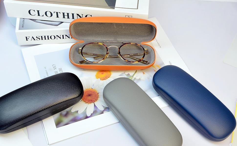 Eyeglasses in an orange case surrounded by blue, gray, and black hard shell cases. Books with 'CLOTHING' and 'FASHIONING' visible on spines in background.