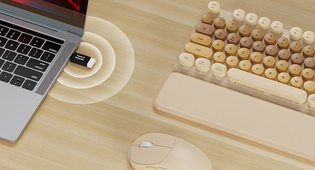 USB receiver plugged in laptop connects beige wireless keyboard mouse combo with wrist rest on desk