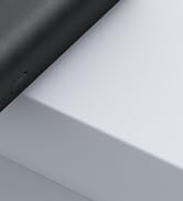 Close-up of a corner where two surfaces meet, showing a black textured material on top and a smooth light gray surface below.