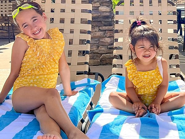 More little girls in summer clothes, smiling while together with beach towels
