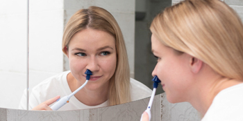 smiling lady using the SinuPulse Elite to relieve allergy and sinus symptoms