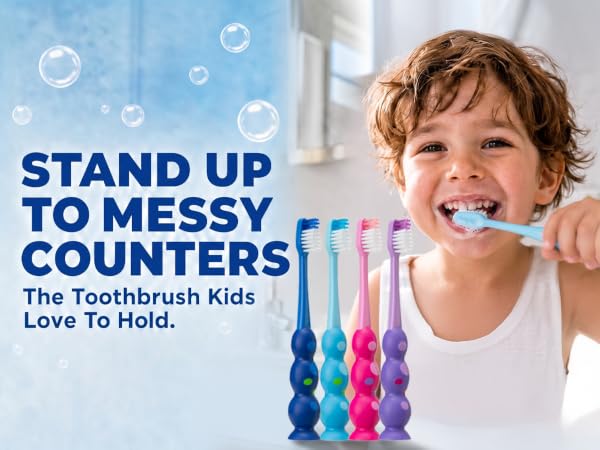 Child brushing teeth with blue toothbrush; 4 colorful kids&amp;#39; toothbrushes displayed on counter