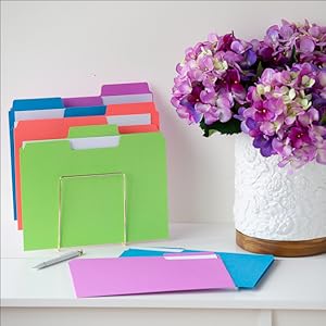 Smead colored file folders on a white desk, white pen, flower vase with purple Hydrangeas