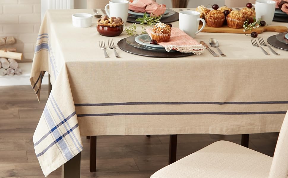 A dining table set with a DII Blue French Stripe Tablecloth