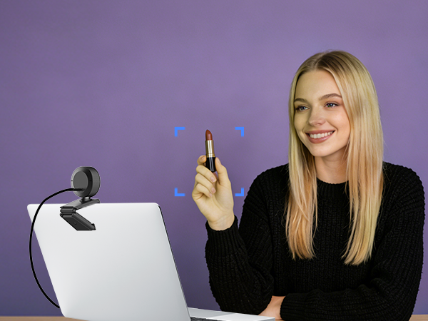 Woman in black jacket holds up a small device component while standing next to white cylindrical product on stand against purple background.